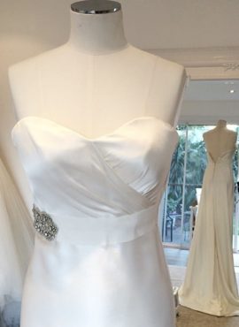 Elegant and sophisticated Rhonda Hemmingway Couture custom made wedding dress made from exquisite ivory Dutch silk satin. Strapless with sweetheart neckline and slimfit sheath silhouette which flatters the figure, flowing into a stunning train. Attached bridal belt with embellished jewel detailing to complete the look. This designer wedding dress is available to try on at The Barefaced Bride studio.